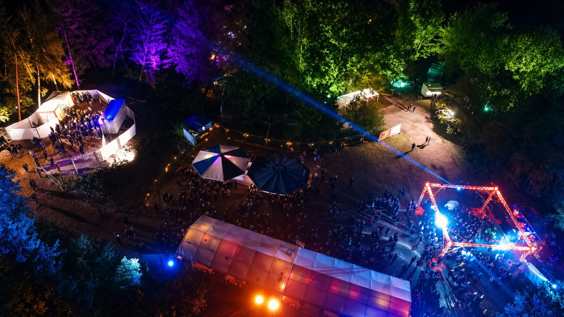 Die Steinbruchfete von oben: Bühne, Zelte und bunt beleuchtete Bäume